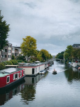 A picturesque Amsterdam canal lined with boat houses and a small boat navigating the water.