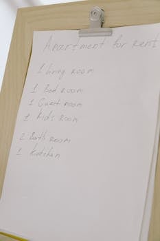 Close-up of a handwritten rental listing on paper clipped to a wooden board.